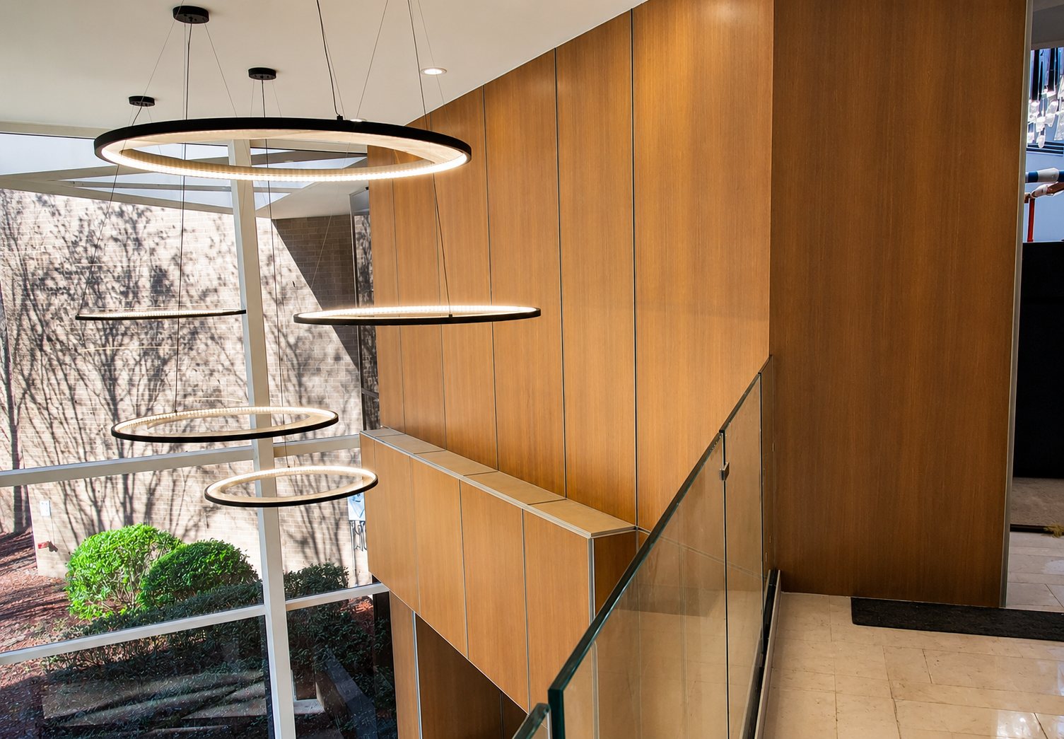 Wood-clad stairwell wall with suspended ring chandeliers